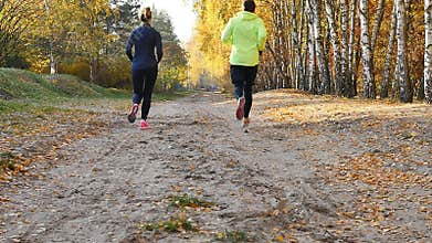 Man and woman running on the autumn woods