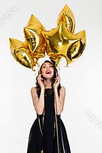 Joyful beautiful young female looking up on star shaped balloons