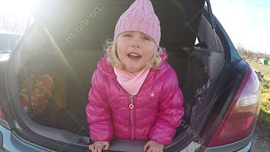 Little girl playing in automobile trunk video