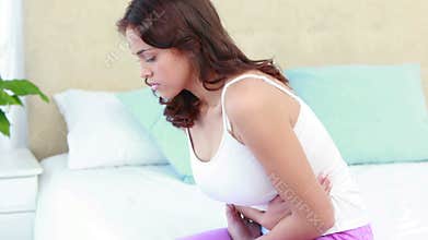 Woman sitting on bed with stomach pain
