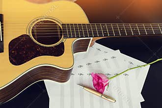 Guitar with pen and rose on the note book,vintage filter.