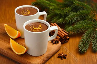 Hot chocolate with orange and spices on the rustic wooden table