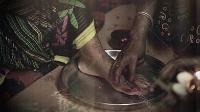 Indian bride doing hindu ritual of foot coloring.