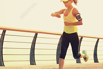 Fitness woman runner checking her running time from smart watch at seaside