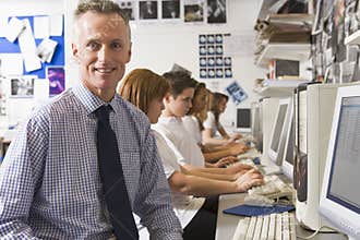 Teacher and schoolchildren studying on computers