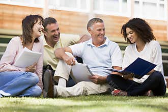 Adult students sitting on a campus lawn