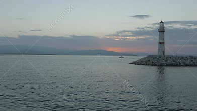 Lighthouse and breakwater with fishing boat moving