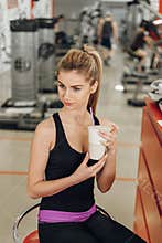 Beautiful blonde in the gym drink protein