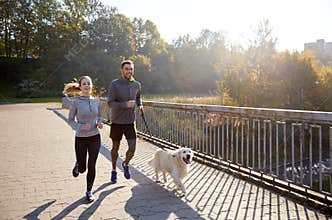 Happy couple with dog running outdoors