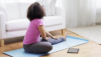 African woman with tablet pc exercising at home