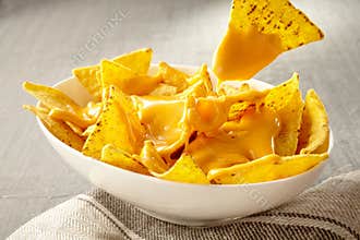 Chip pulled out of bowl of cheese covered nachos