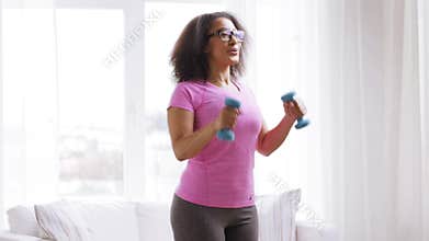African woman exercising with dumbbells at home