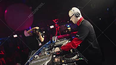 go go girl in blue bikini dance on party in nightclub. Dj at turntable.