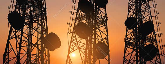 Silhouette, telecommunication towers with TV antennas and satellite dish in sunset, panorama composition