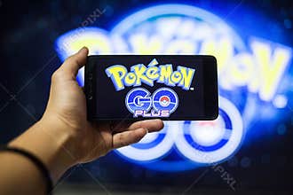 Hand holding a cellphone playing Pokemon Go game with blur background