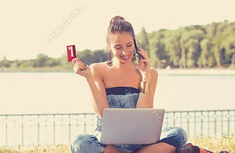 Woman shopping on line holding credit card talking on mobile phone