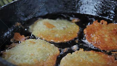 Potato pancakes fried in a pan with vegetable oil.