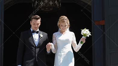 Wedding couple go out of the church after ceremony