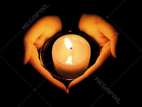 WOMAN'S HANDS LIT BY A CANDLE