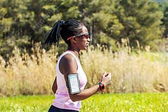 African teen running with fitness activity tracker.