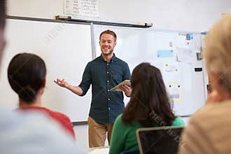 Male teacher listening to students at adult education class