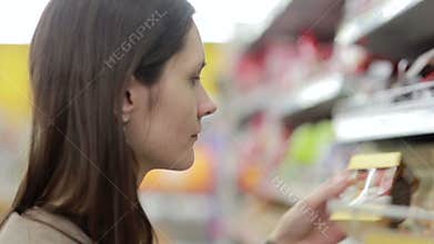 Girl selects the item on the shelves in the store