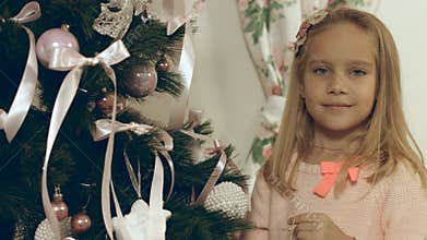 Beautiful blue-eyed girl hangs a homemade Christmas toy on Christmas tree