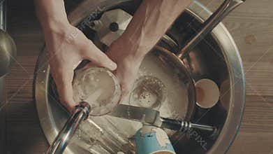Man`s hands washing dishes in the kitchen after breakfast