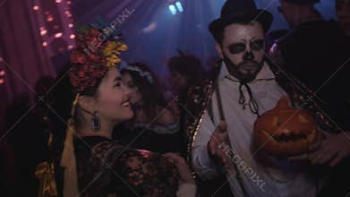 Group of young friends in costumes dancing at night club halloween party