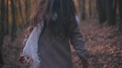 Small teenage girl with long brunette hair and stylish look. Scared little girl running in the forest, she looks around