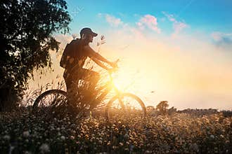 Biker on mountain bike adventure in beautiful flowers nature of summer sunset