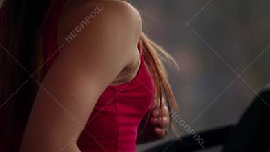 Back and side view of a woman running on a treadmill while working out in a sport club. Training in a gym.