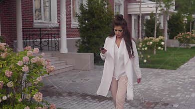 Young beautiful business woman walking down the street using her smartphone