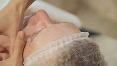 Woman middle-aged take face and neck lymphatic, drainage massage in spa salon