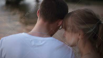 Close-up back view. young lovers man and woman walking along the edge of the lake at sunset
