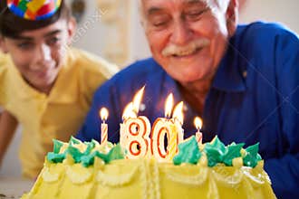 Boy and Senior Man Blowing Candles On Cake Birthday Party