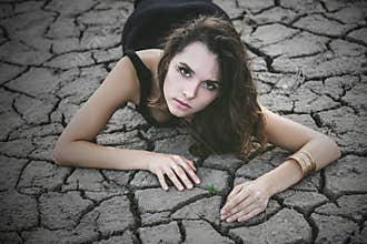 Woman protects a small sprout on a cracked desert soil