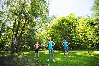 Fitness group doing yoga in park on a sunny day