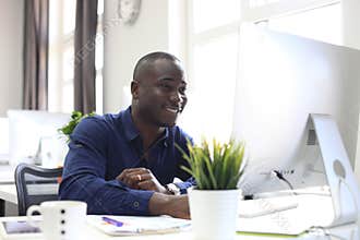 Portrait of a happy African American entrepreneur displaying computer in office.