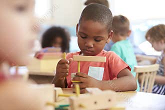 Montessori Pupil Working At Desk With Wooden Shapes