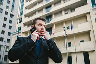 Serious man with a beard businessman talking on the phone on the background of the urban landscape