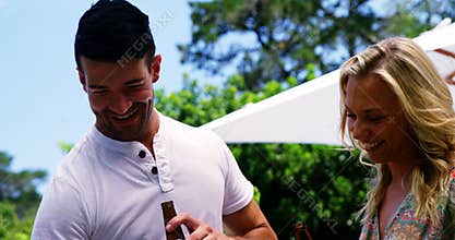 Group of friends having a bottle of beer while preparing barbeque