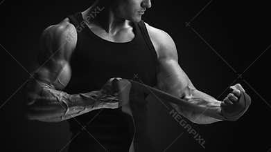 Close up photo of strong man wrap hands Bodybuilder man is wrapping hands with boxing wraps isolated on black background Strong h