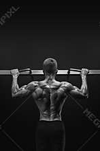 Power muscular bodybuilder guy doing pullups in gym. Fitness man