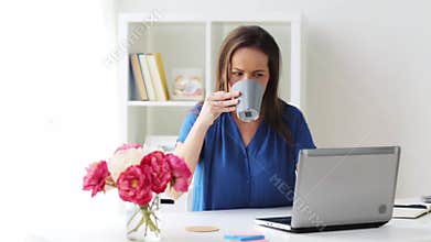 Woman with laptop and coffee at home or office