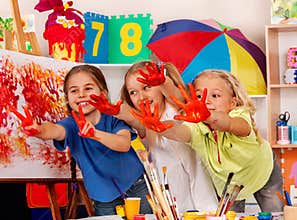 Children painting finger on easel. Small students in art school class.