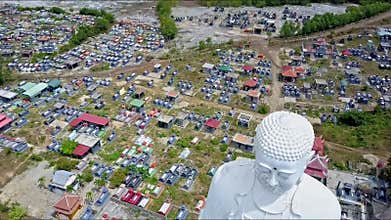 Drone Flies Close to Giant Buddha Statue Head against Town