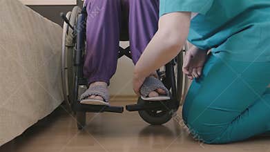 Female caregiver helping senior woman to put her shoes
