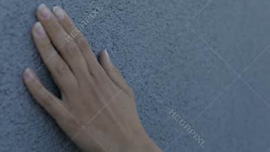 Female hand gently strokes the texture wall
