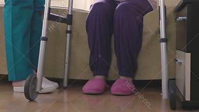 Care assistant teaching elder disabled woman how to walk with walker